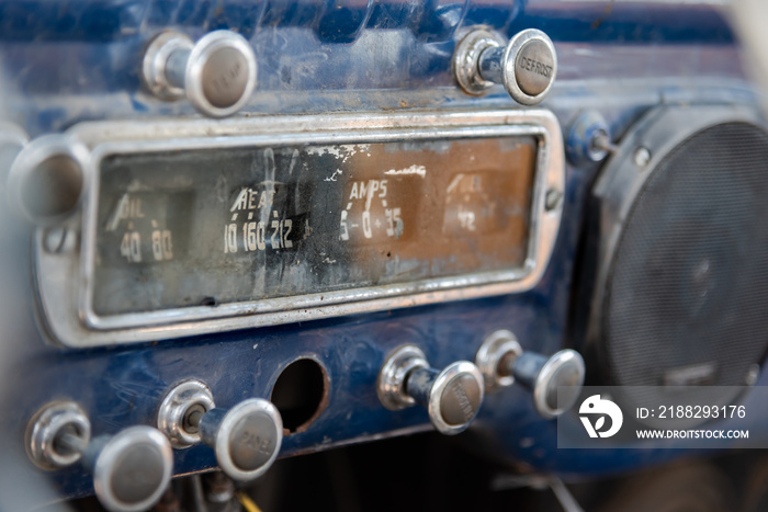 Dashboard at front of abandoned vintage truck with ammeter, oil indicator, various knobs