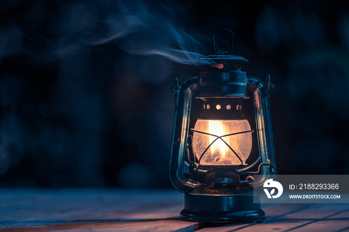 antique kerosene lamp with lights on the wooden floor on the lawn at night