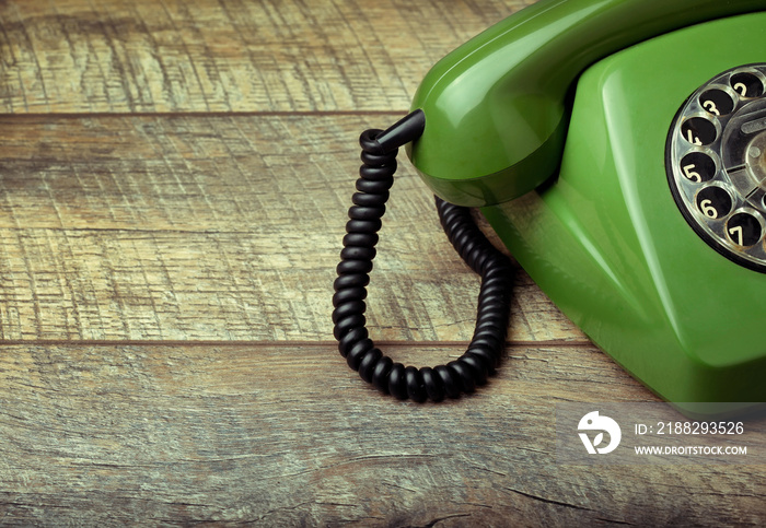 Old green telephone on a wooden background