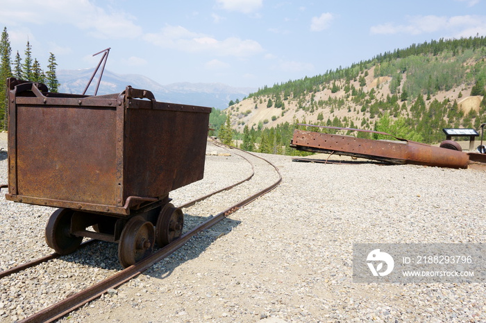 Steel ore cart sits on a railing outside of the mine