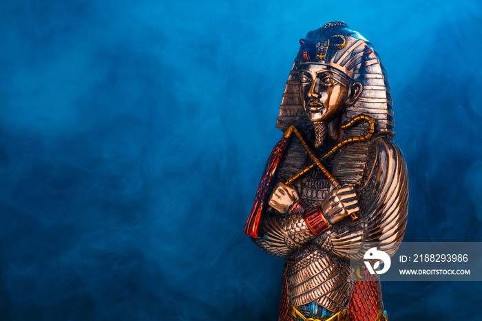 egyptian golden pharaoh statue in blue fog on black background