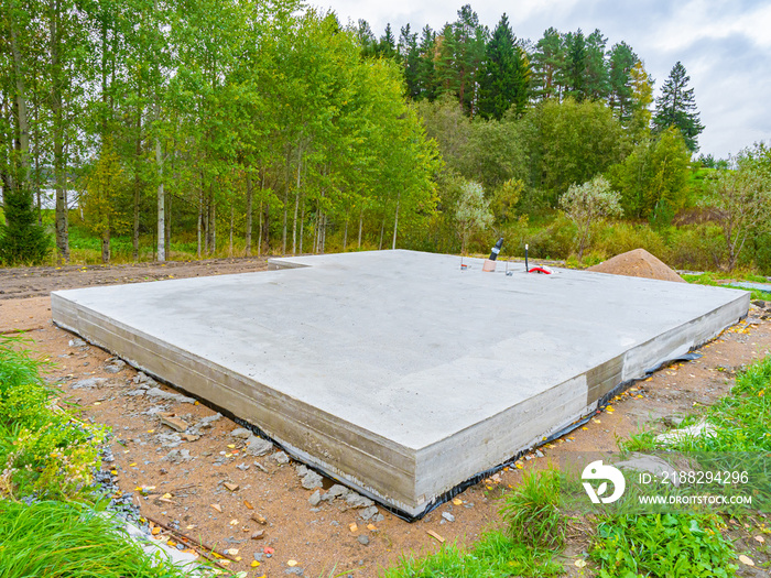 Concrete foundation next to trees. Construction near forest. Construction site with foundation. Foundation as a symbol of construction of a cottage. Building of a country cottage.