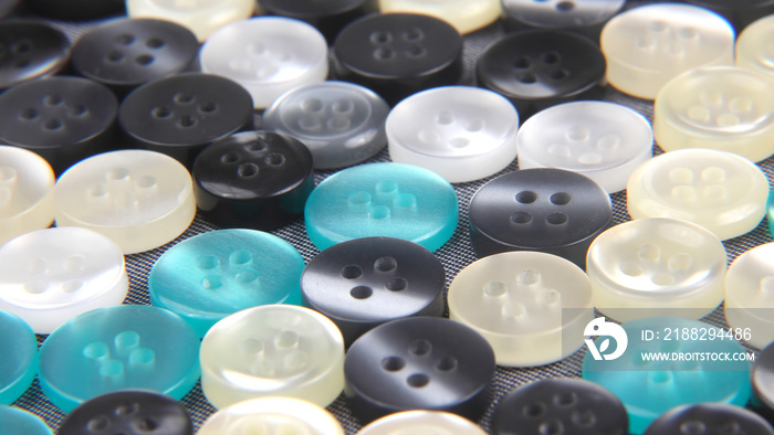 Plastic shiny buttons for clothes on a fabric background. Fashion and clothing. Factory industry