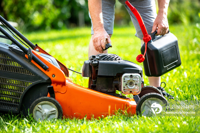 Man refueling the lawnmower on his huge garden, gardening concept