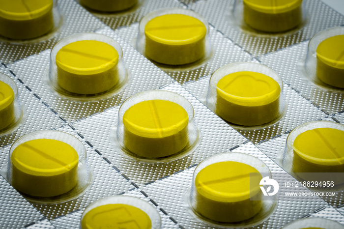 Macro shot detail of yellow tablets pill in blister pack. Full frame of tablet pills