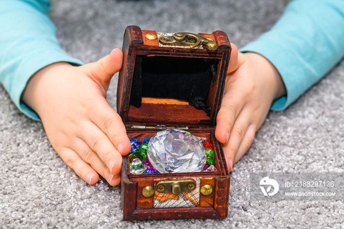 Five year old boy holding a treasure chest full of multicolored gems in his hands