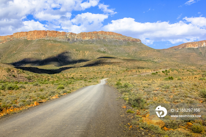 African safari in 4x4. Adventure in the African desert. Gravel mountain road in the dramatic sky, Karoo National Park in the summer, Western Cape province of South Africa.