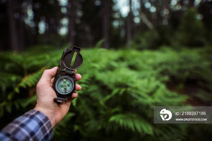 Mann im Wald hält Kompass in der Hand