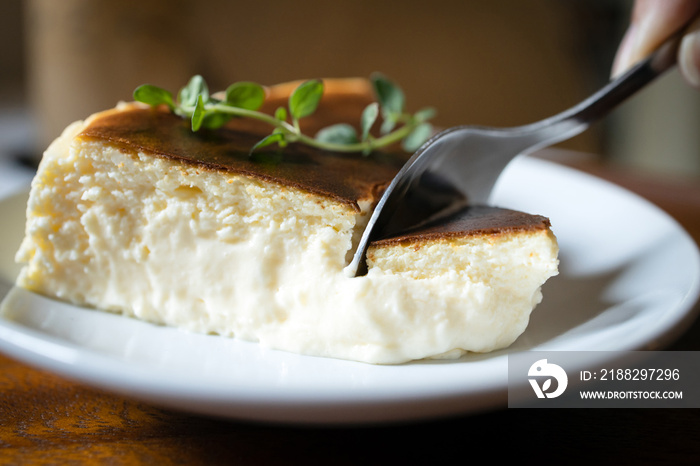 Close Up,Basque Burnt Cheesecake,Tarta de Queso or San Sebastian Cheesecake on a white plate with a spoon to scoop the soft cheese cake,delicious spanish dessert recipe,sweet food made with cream