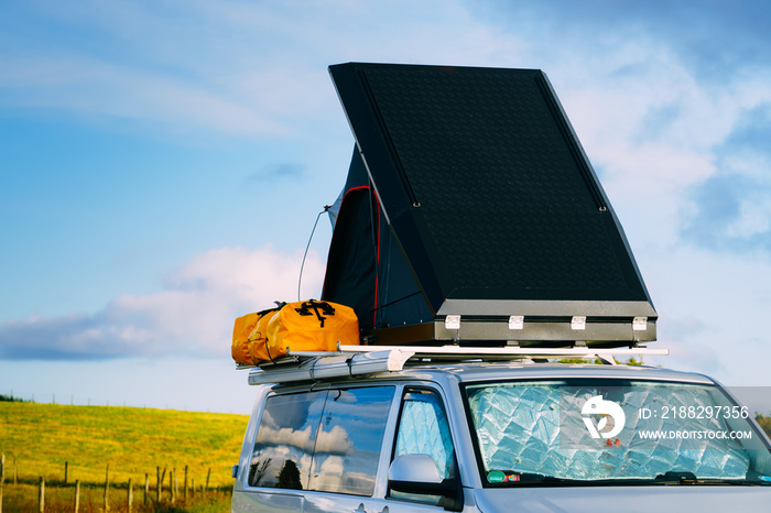 Camper van with tent on roof on roadside