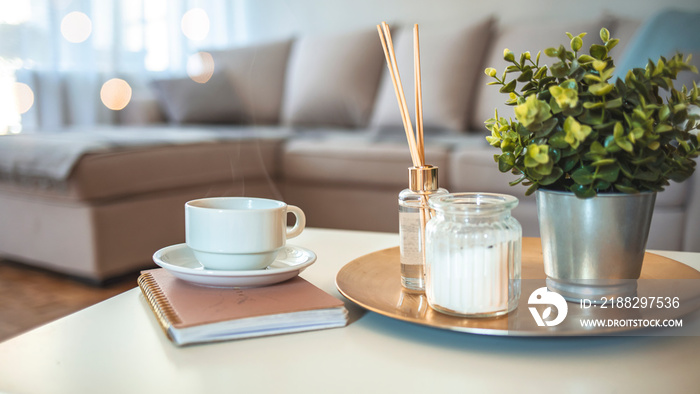 Hygge and aromatherapy concept - Coffee, candles, book and aroma reed diffuser on table at home. Home fragrance in sticks. Air freshener, diffuser and aromatherapy concept