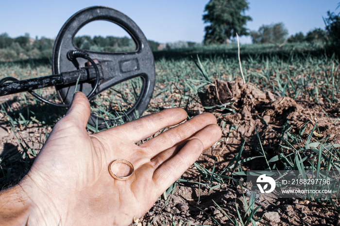 an antique gold ring in the hand of a searcher, found on an old tract with the help of a metal detector, the foreground and background are blurred with a bokeh effect