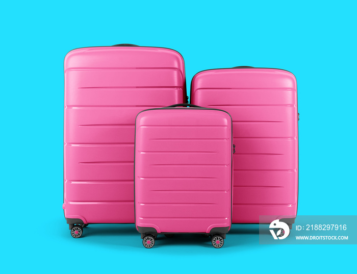 Set of stylish pink suitcases for travel on blue background.
