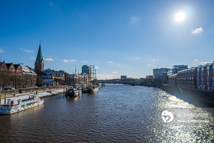 View from footbridge to river weser with some boats in the sunlight in bremen in winter