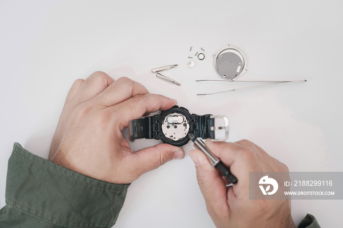 A man use pliers to clamp the digital watch battery remove and change in repairing broken wristwatches on white table