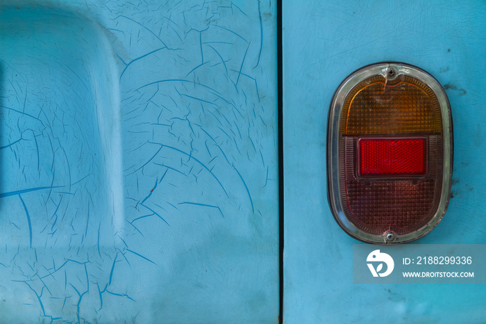 Close-up turquoise blue old car with crack and scratch color surface background. Abandoned retro truck with decay textured and the aged oval tail lamp. Selective focus and copy space.