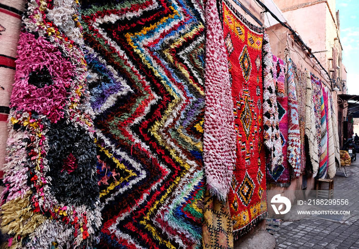 Carpet shop with colourful moroccan berber rugs on wall display  in a street souk market in the centre of medina in Marrakech, Morocco.