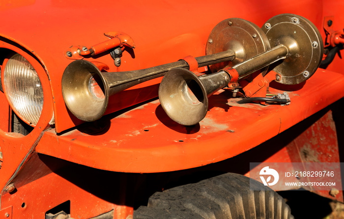 Pair of vintage brass truck air horns on a red vehicle wing.