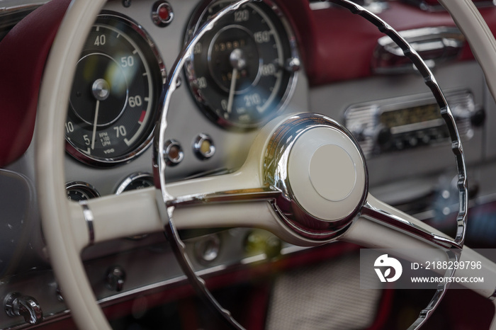 Selected focus at unique decorated shiny and white steering wheel and blur dashboard inside vintage classic old car.