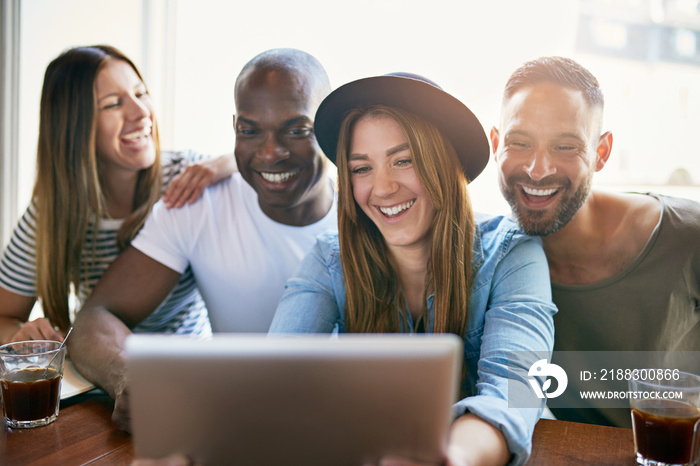 Cheerful group of young co-workers sharing tablet