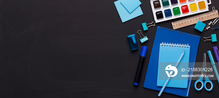 Blue colored school stationery on black board with copy space