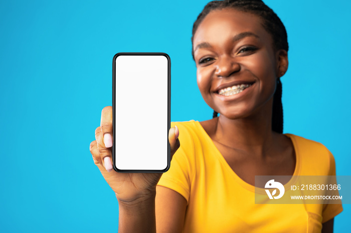 Girl Showing Smartphone Blank Screen Over Blue Studio Background, Mockup