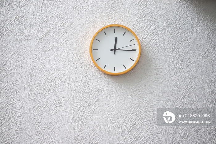 混凝土墙上的黄色塑料时钟在中午显示时间，文本免费复制空间。