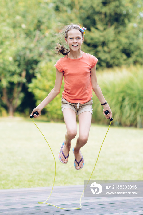 夏天，一个大笑的十几岁女孩在露台上的花园里跳绳