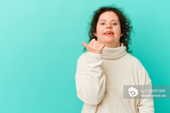 Woman with Down syndrome isolated points with thumb finger away, laughing and carefree.