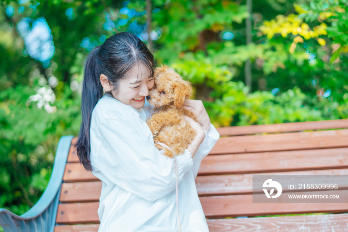 公園で犬と遊ぶ女性（抱く）