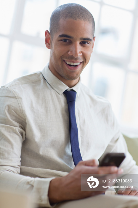 肖像微笑的年轻商人使用智能手机