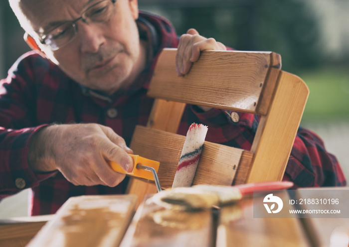 Man varnishing chair in garden