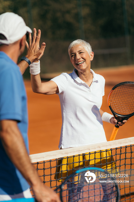 Tennis Coach Practicing Service with Senior Woman on Outdoor Tennis Class. Giving high five.