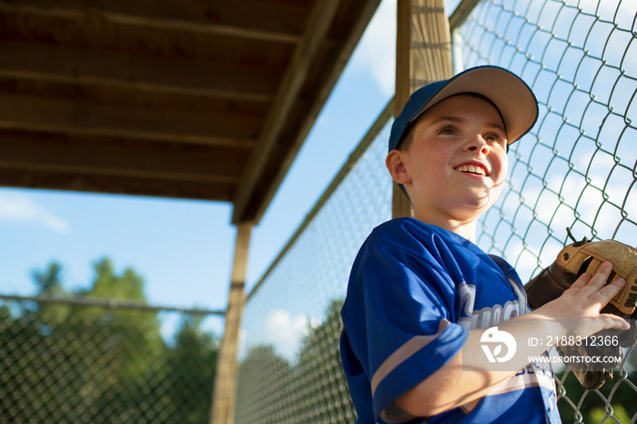 Smiling baseball player standing near chainlink fence