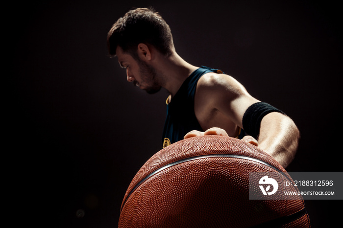 黑色背景下一名篮球运动员拿着篮球的剪影