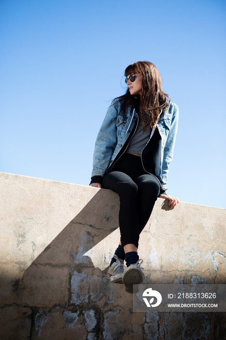 Young woman sitting on wall