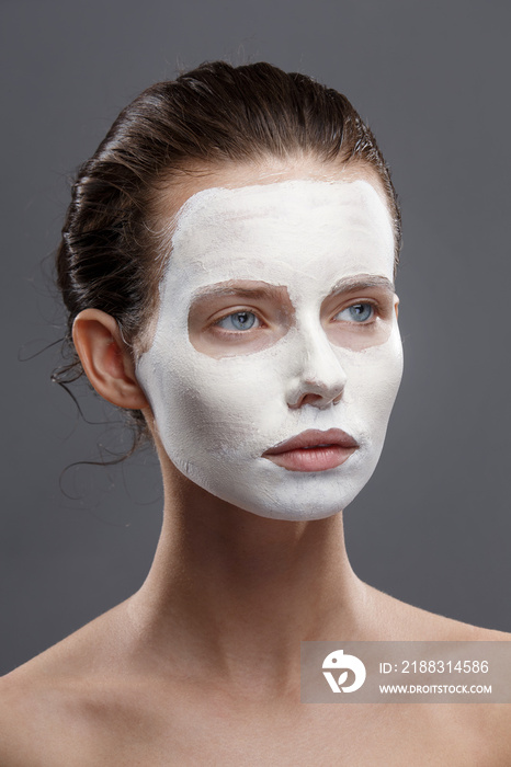 Beautiful girl is applied a white cosmetic mask from black dots. Isolate, studio