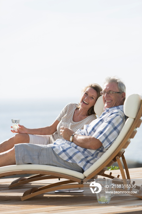 Portrait happy senior couple relaxing on lounge chairs