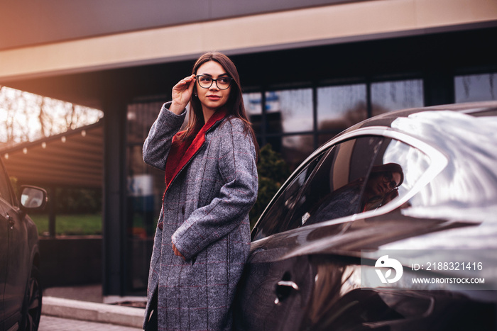 Fashion business woman in eyeglasses standing near her car