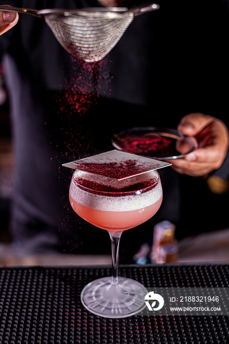 Cold pink strawberry cocktail in a glass. Restaurant serve, on a black background.