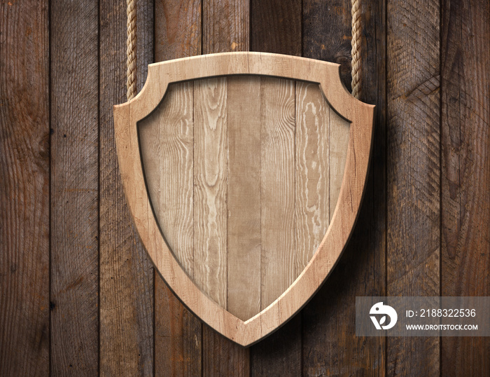 Defense protection shield shaped sign made of bright wood and hanging on ropes with wood planks back