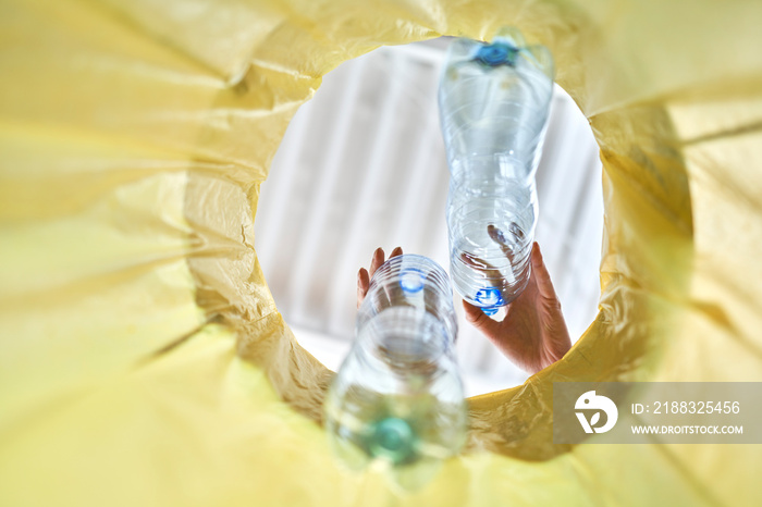 Plastic bottles falling into a yellow garbage bag