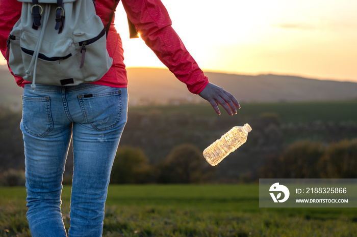 Plastic pollution environment. Hiker throwing away plastic bottle in nature.