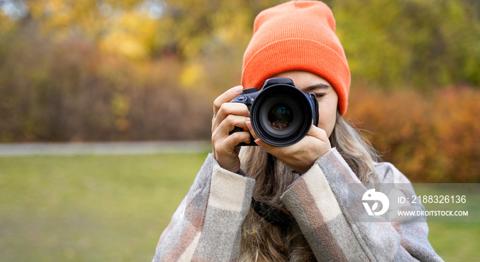 Girl with camera outdoors. Woman takes pictures. Hobby leisure or profession