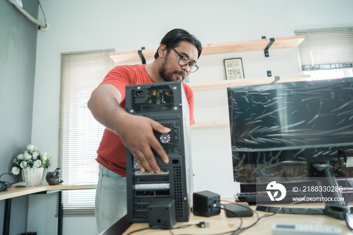 portrait of asian young man fix a problem with server of personal computer in office room