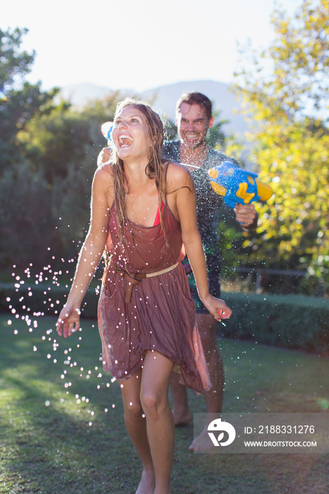 Playful couple with squirt gun in backyard