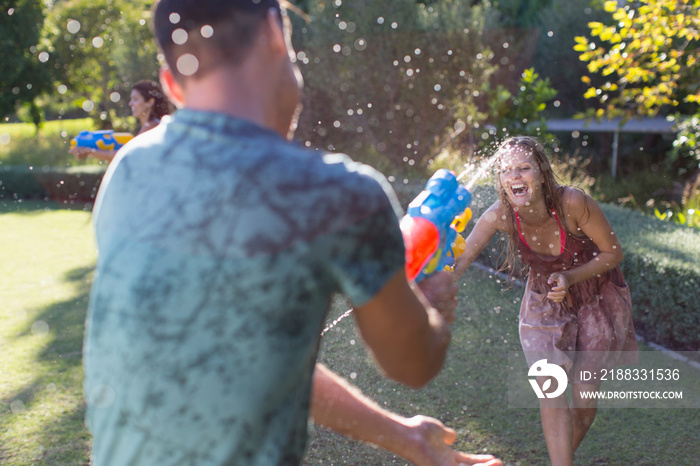 Playful couple with squirt guns in backyard