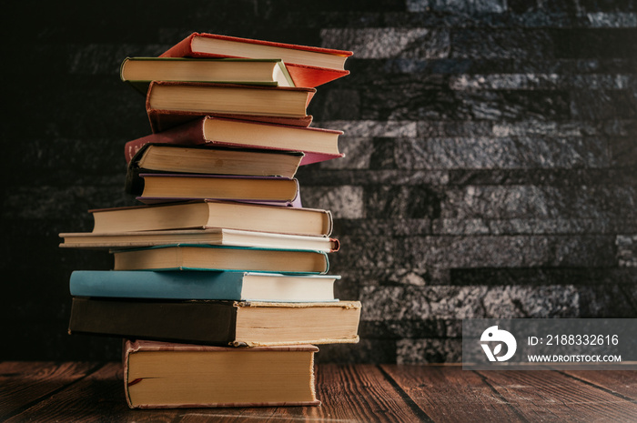 Stack of books in the colored cover lay on the wood table  with dark backround. Education learning c