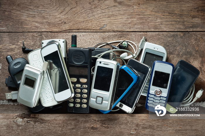 Old and obsolete mobile phone or cell phone and accessories on space of old wood background