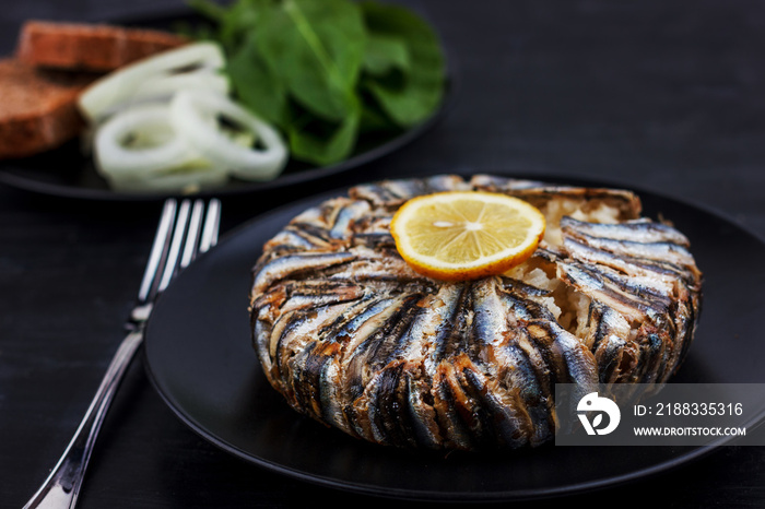 Pilaf with hamsi anchovy fish. Traditional Turkish food - Kapama Pilav - on black wooden table.